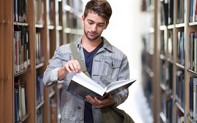 A student browsing a book in the library with the help of a learning management system